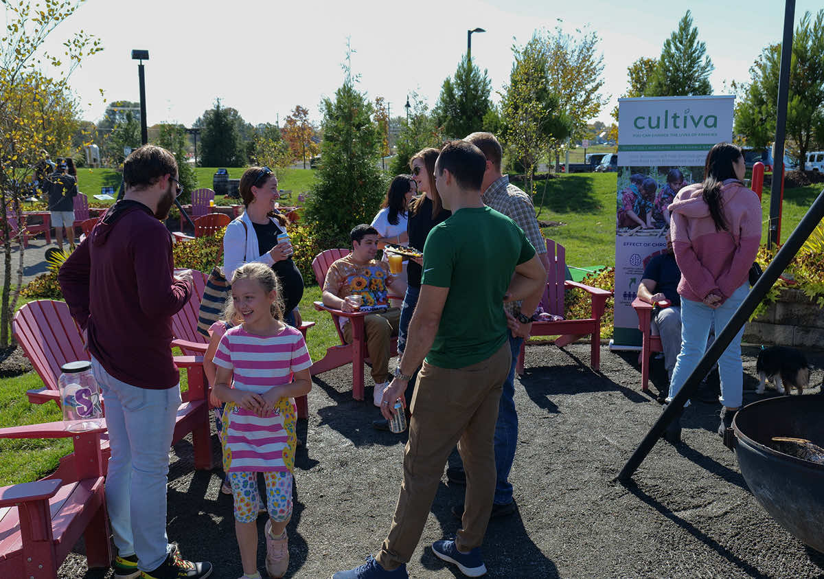 A community gathering with people enjoying refreshments and socializing in a park setting.