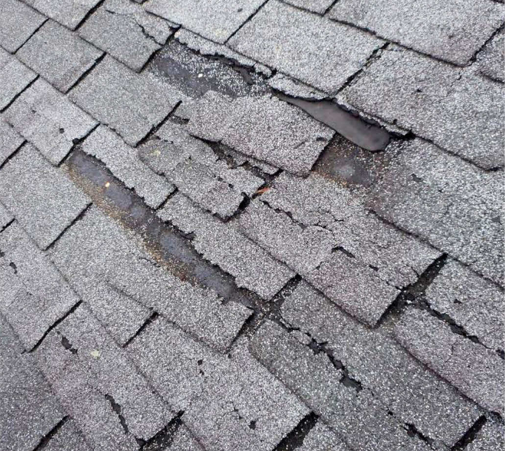 Close-up of damaged asphalt roof shingles showing wear and tear