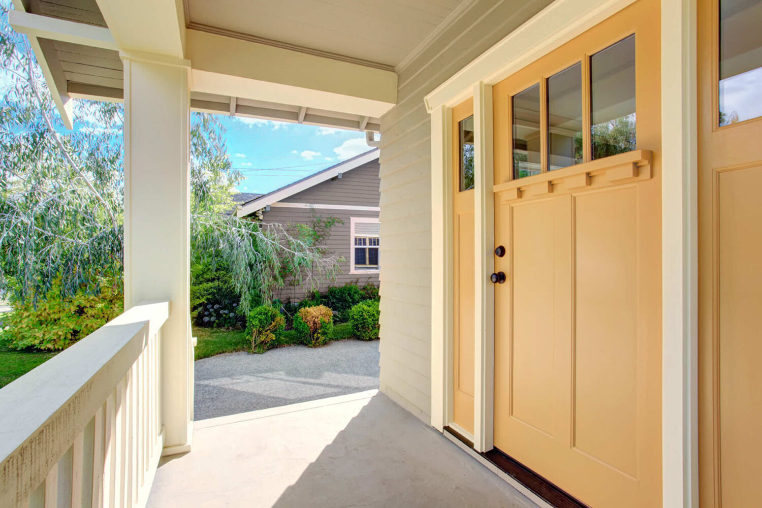 A welcoming front entrance with a yellow door and a view of a landscaped front yard.