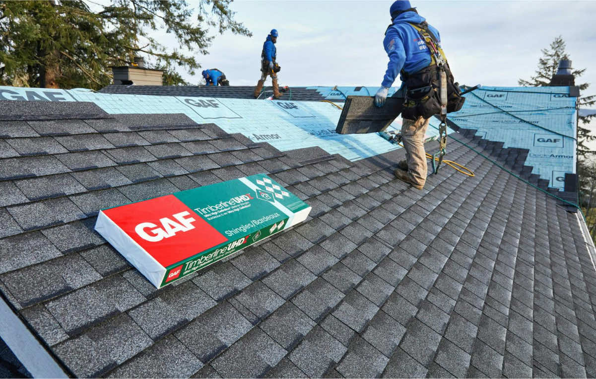 Workers installing GAF Timberline shingles on a residential roof