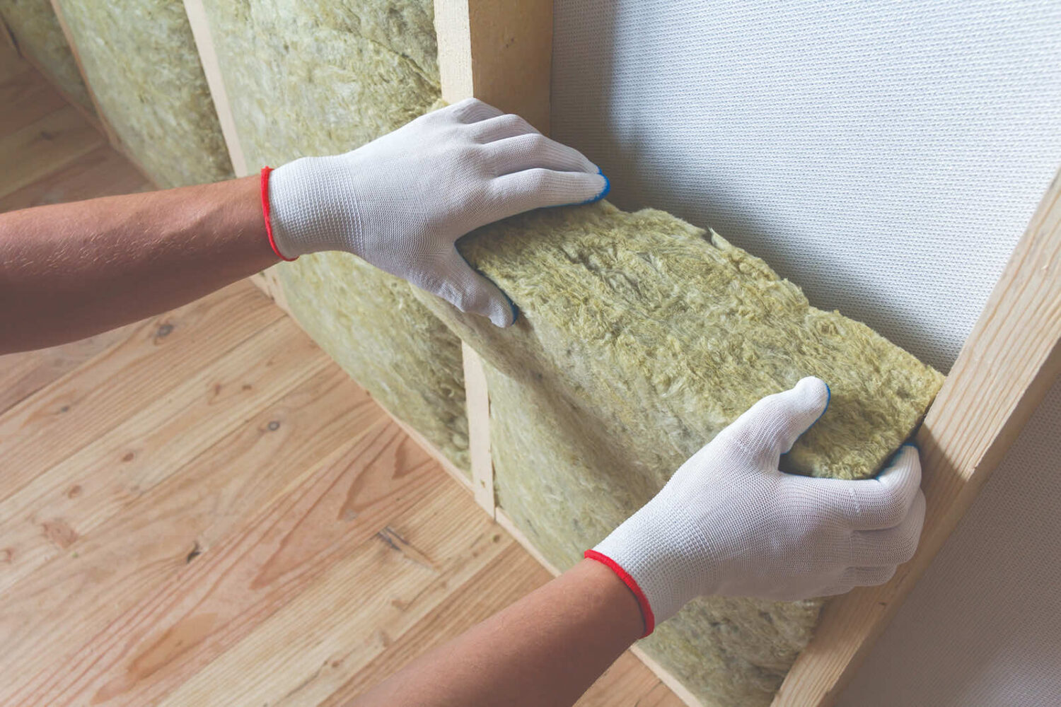 A person wearing gloves installing insulation material