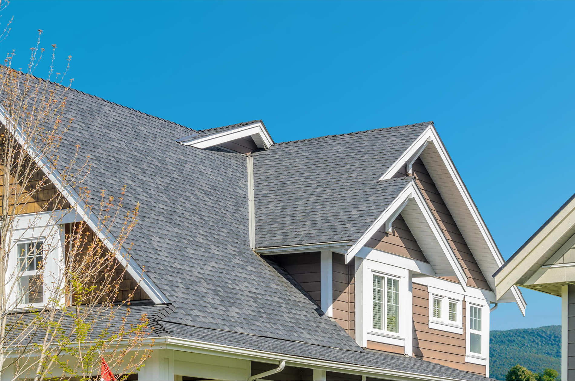 Close-up view of a modern residential roof with shingles against a clear blue sky