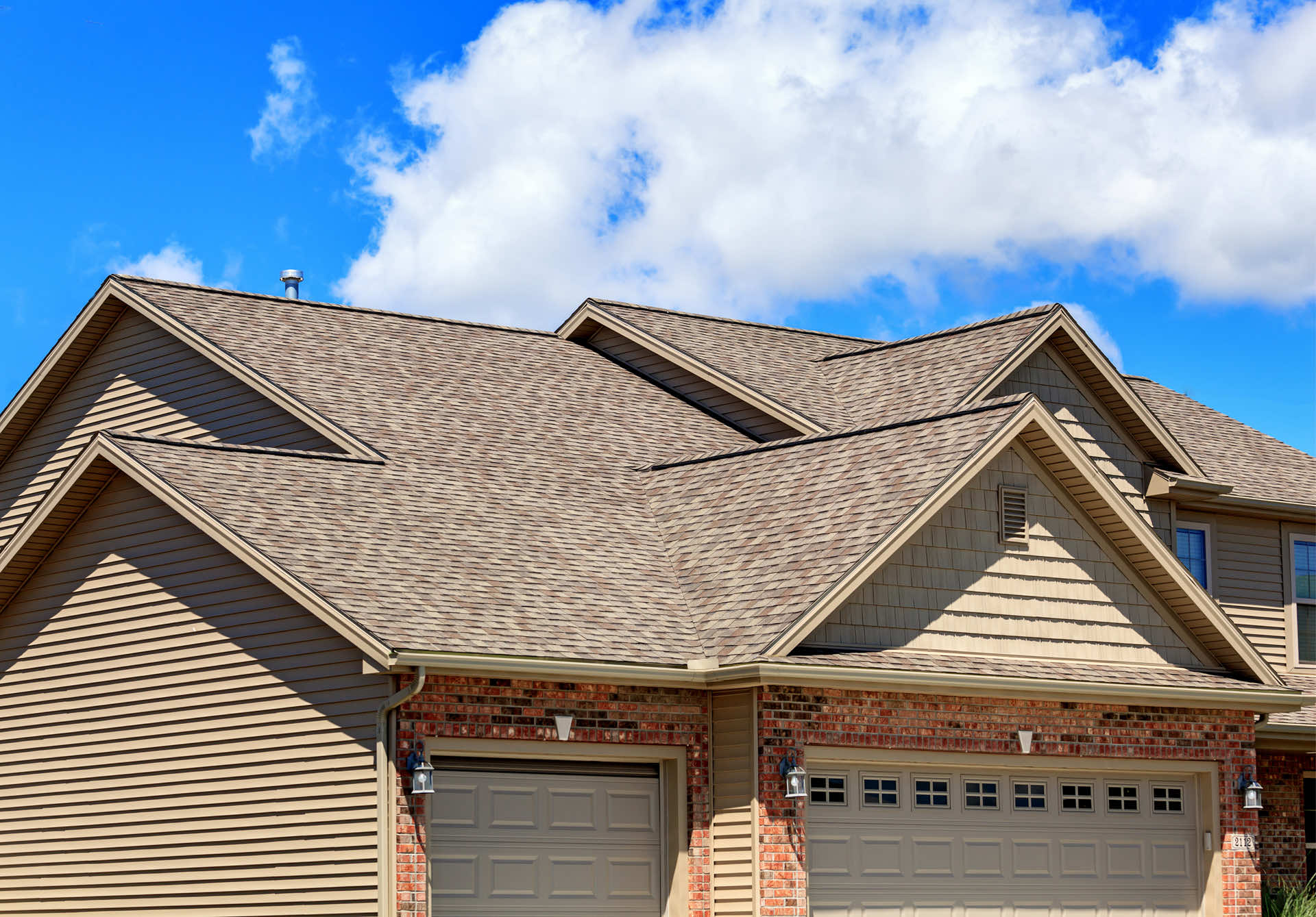 Close-up view of a residential roofing installation with brown shingles and clear blue sky