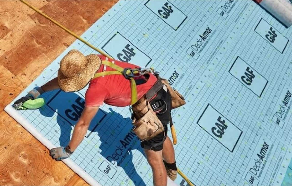 Worker installing GAF Deck Armor roofing underlayment on a residential roof
