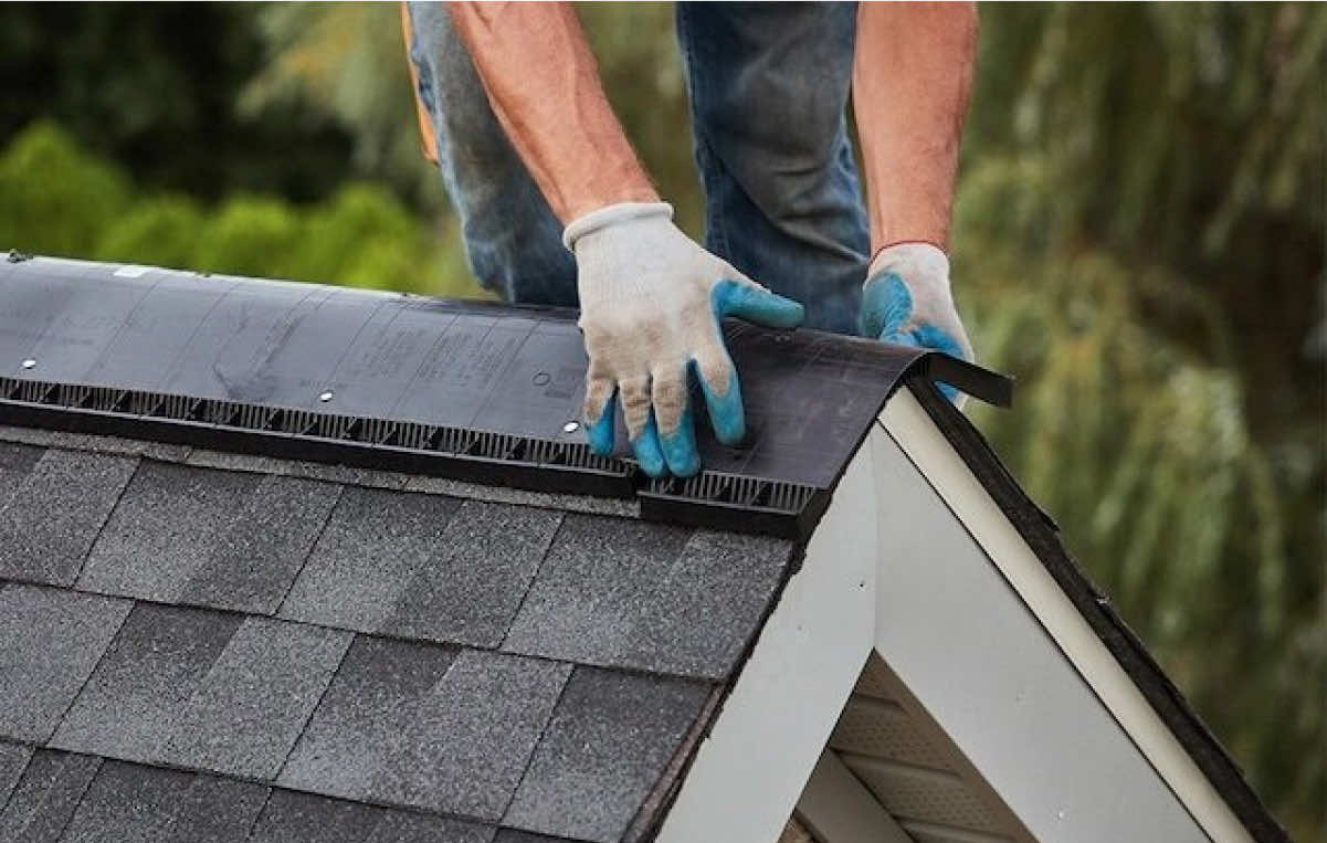 Worker installing roofing material on a residential roof