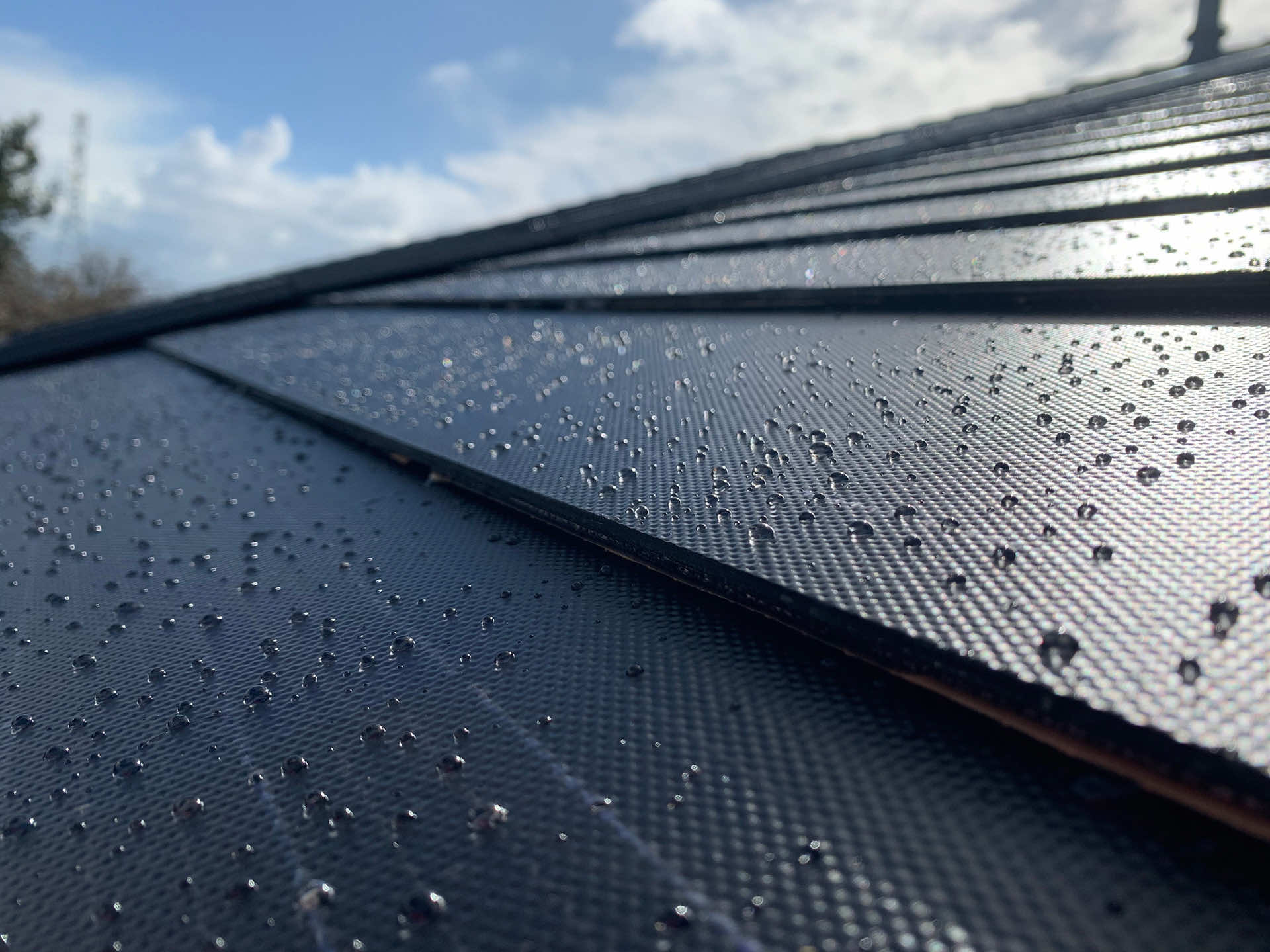 Close-up of a textured roofing material with water droplets on the surface