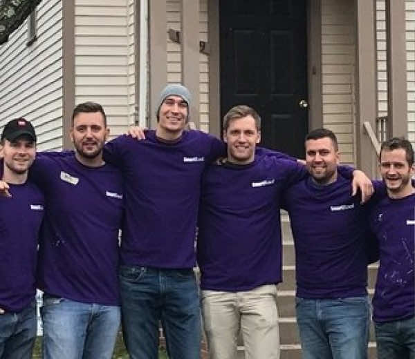 SmartRoof team posing together in purple shirts at a team event.