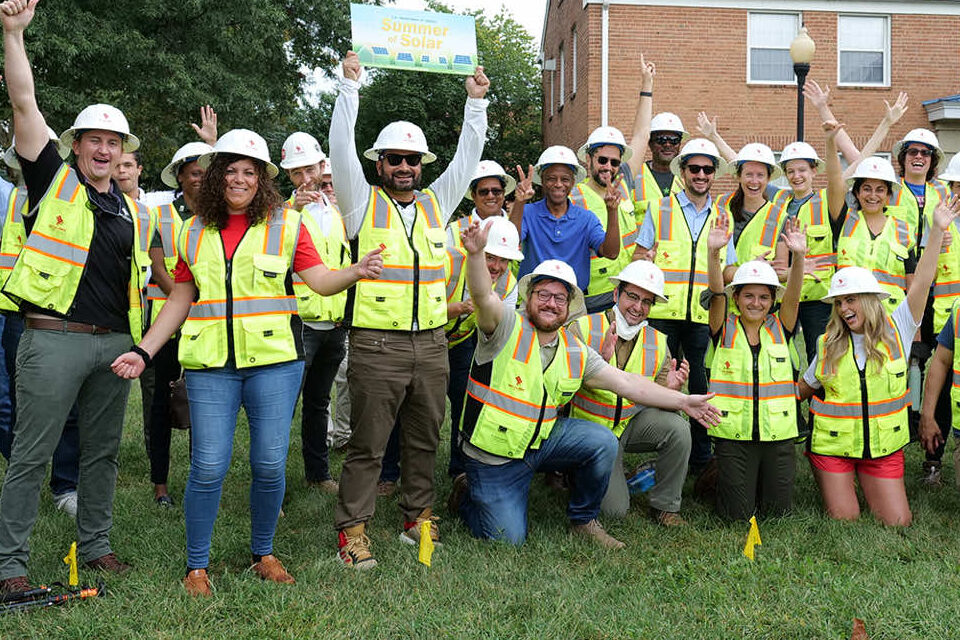 Team of roofing and solar installation crew celebrating during a summer event