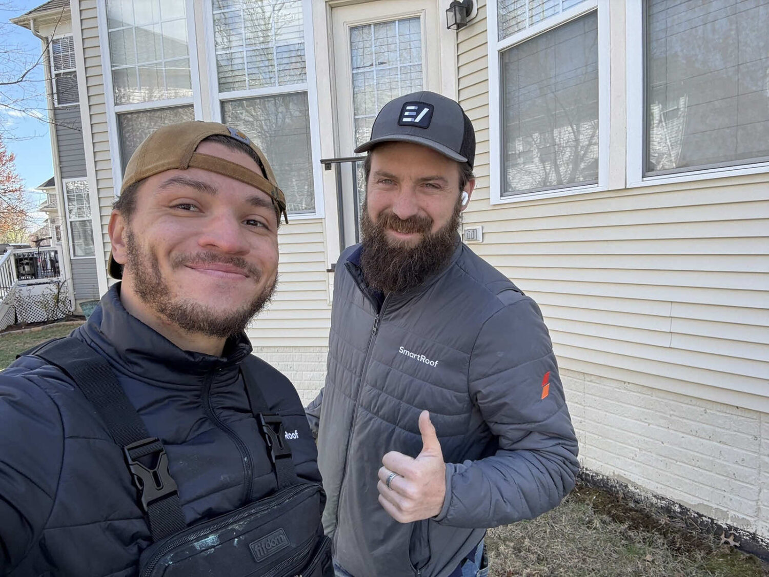 Two SmartRoof team members smiling in front of a residential home