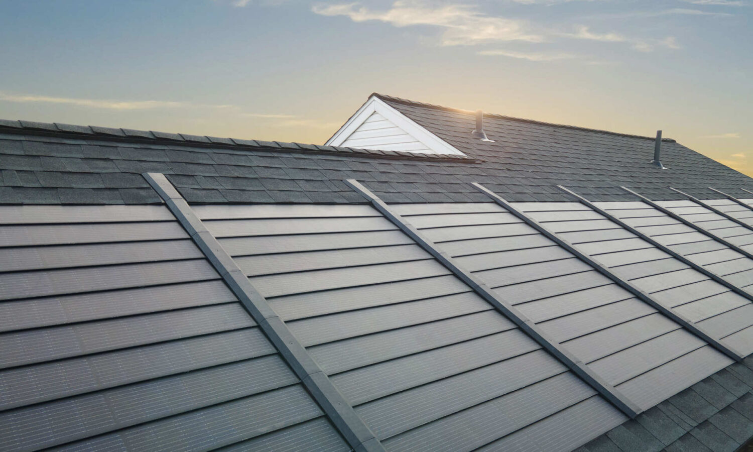 Roof with solar shingles reflecting sunlight during the day