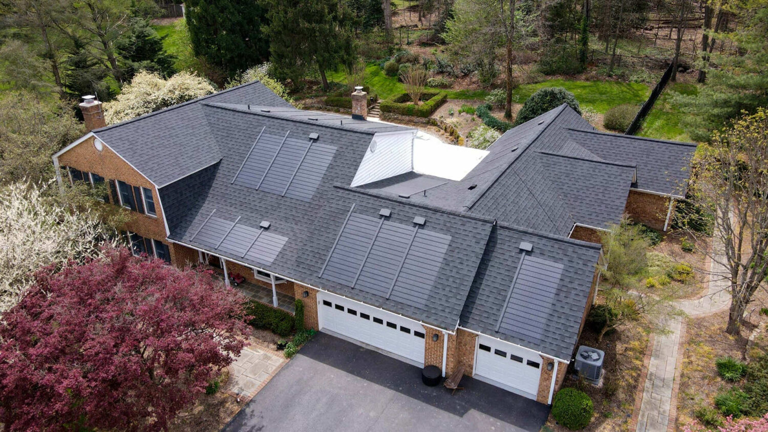 Aerial view of a residential home featuring solar shingles on the roof.